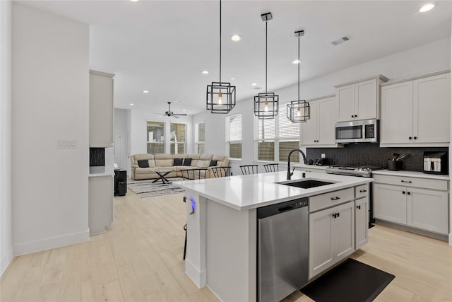 kitchen featuring a sink, visible vents, light countertops, appliances with stainless steel finishes, and decorative backsplash