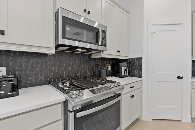 kitchen featuring white cabinetry, light wood-style floors, light countertops, appliances with stainless steel finishes, and decorative backsplash