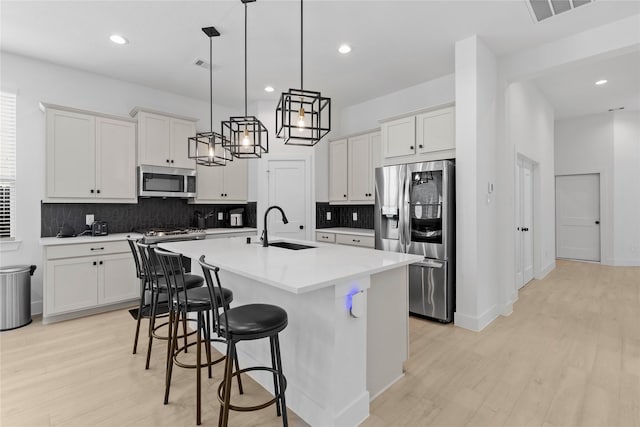 kitchen featuring appliances with stainless steel finishes, white cabinets, visible vents, and a sink