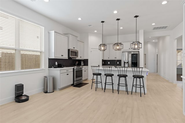 kitchen featuring stainless steel appliances, backsplash, a kitchen bar, and visible vents