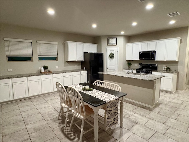 kitchen featuring visible vents, recessed lighting, a kitchen island with sink, black appliances, and white cabinetry