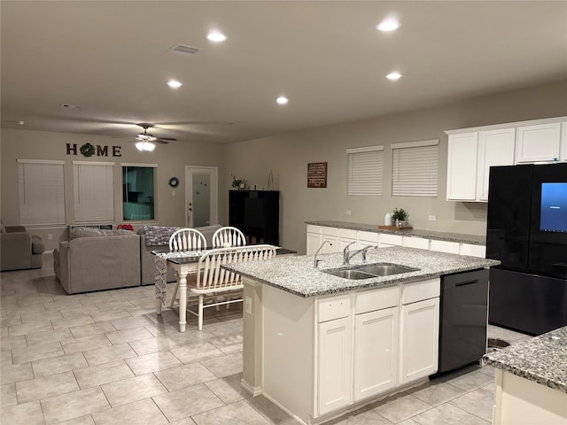 kitchen with visible vents, black appliances, a center island with sink, a sink, and white cabinets