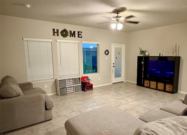 living area with baseboards, a textured ceiling, and a ceiling fan