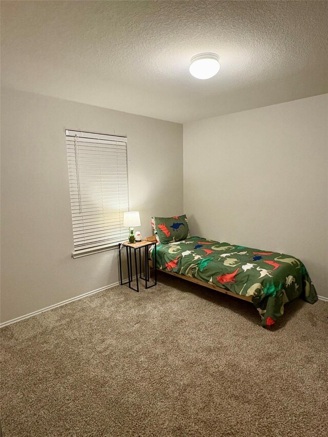 carpeted bedroom with baseboards and a textured ceiling