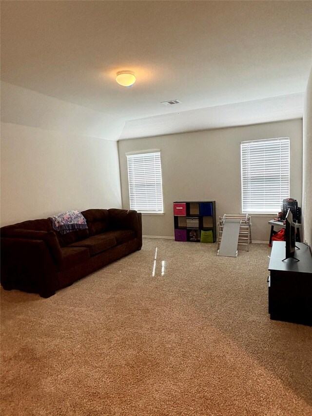 carpeted living area featuring visible vents and baseboards