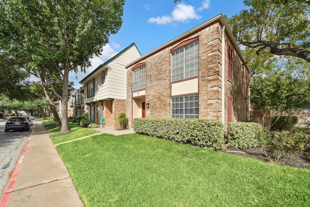 multi unit property with brick siding and a front lawn