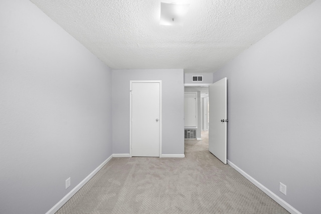 unfurnished bedroom featuring a textured ceiling, carpet flooring, visible vents, and baseboards