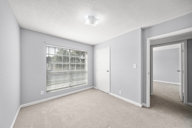 spare room with carpet floors, a textured ceiling, and baseboards