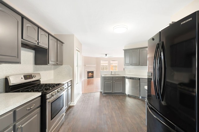 kitchen featuring dark wood-type flooring, gray cabinets, stainless steel appliances, light countertops, and decorative backsplash