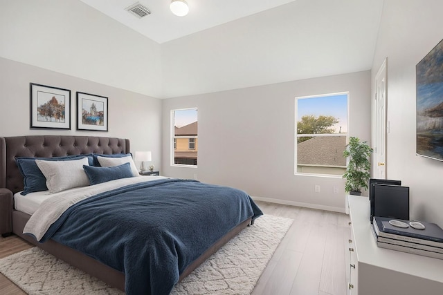 bedroom featuring visible vents, baseboards, lofted ceiling, and light wood finished floors