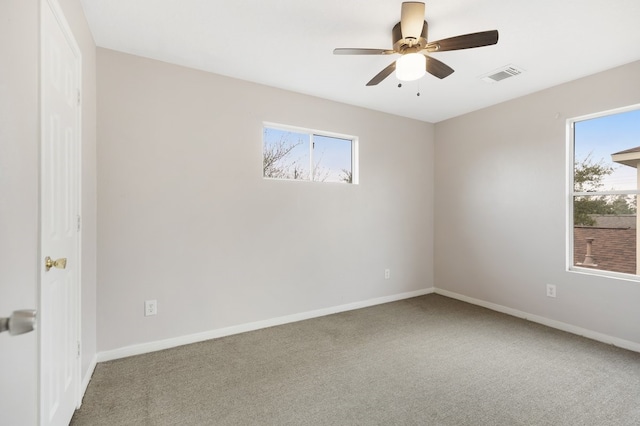 carpeted spare room featuring visible vents, a healthy amount of sunlight, and baseboards