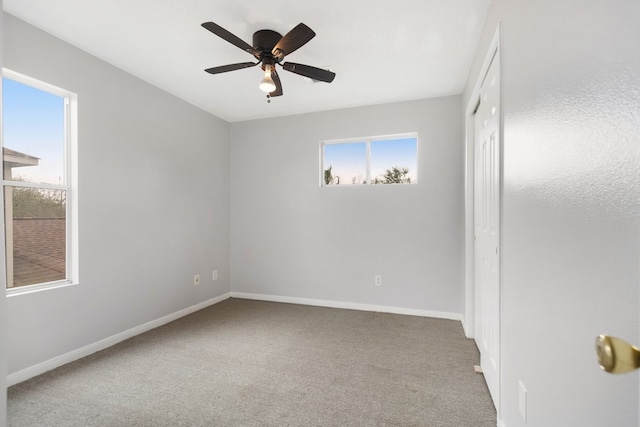 carpeted spare room with baseboards and ceiling fan