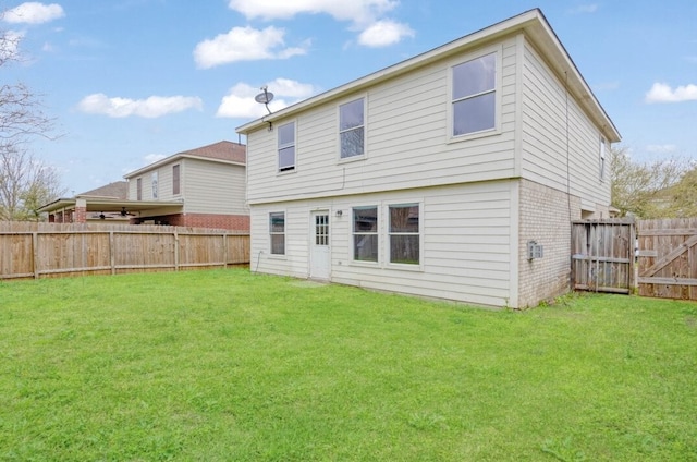 back of property featuring a yard, brick siding, and a fenced backyard