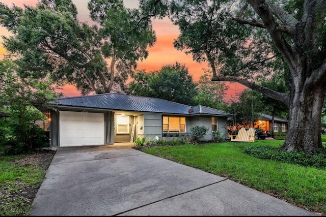 view of front facade featuring metal roof, a front lawn, an attached garage, and driveway