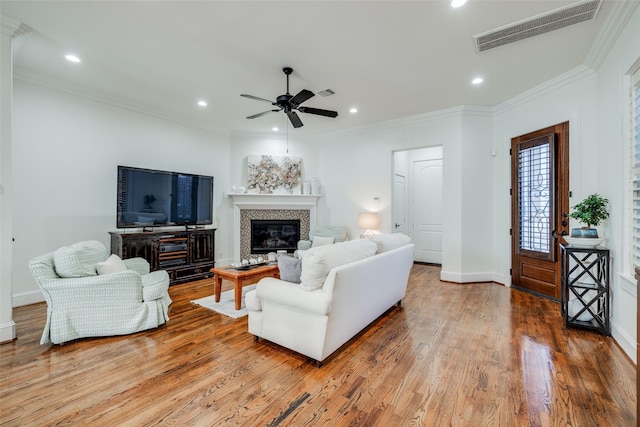 living room featuring crown molding, recessed lighting, visible vents, a glass covered fireplace, and wood finished floors