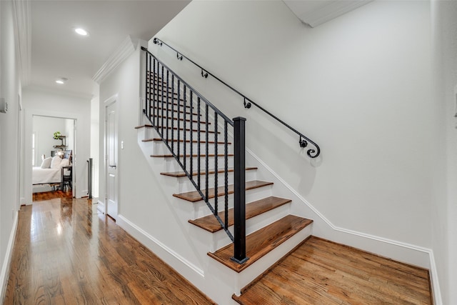 stairway featuring baseboards, recessed lighting, wood-type flooring, and crown molding