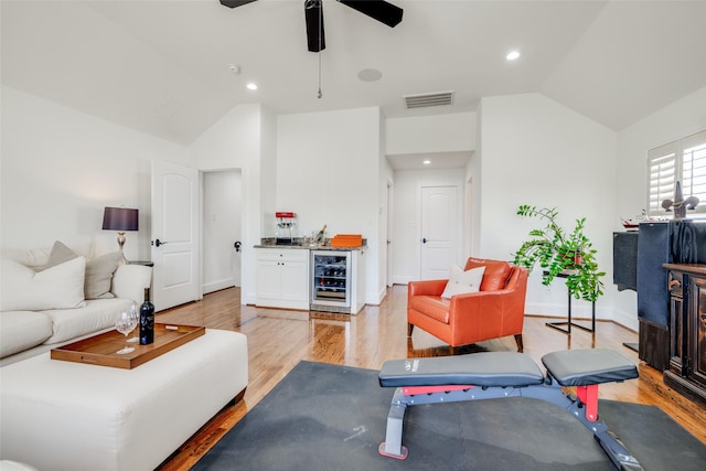 living area featuring wine cooler, a dry bar, light wood finished floors, lofted ceiling, and visible vents