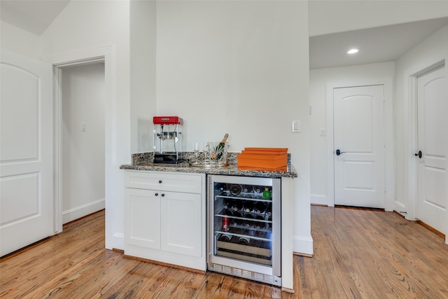 bar featuring a dry bar, light wood finished floors, beverage cooler, baseboards, and recessed lighting