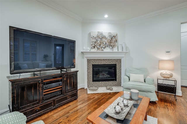 living area featuring a fireplace, baseboards, crown molding, and wood finished floors