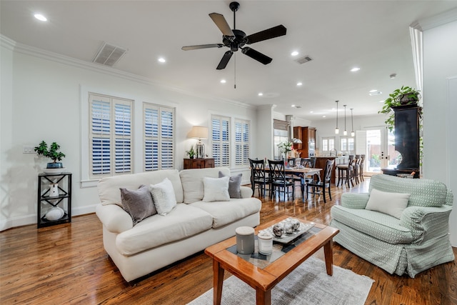 living area featuring visible vents, crown molding, and wood finished floors