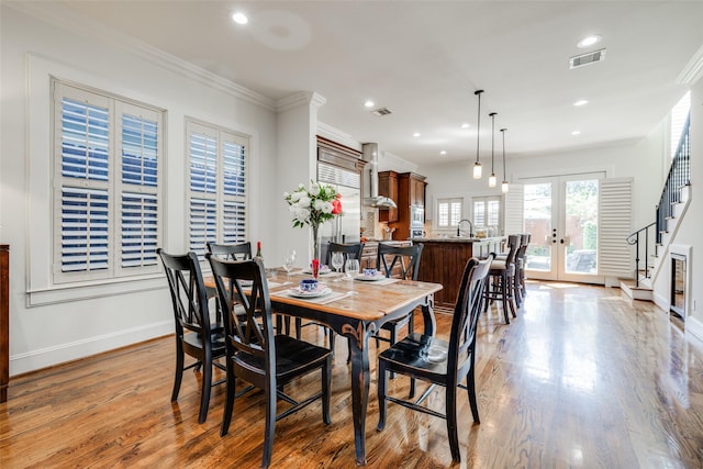 dining room with baseboards, visible vents, ornamental molding, wood finished floors, and french doors