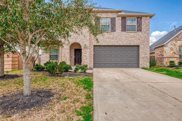 traditional home featuring driveway, an attached garage, fence, and brick siding