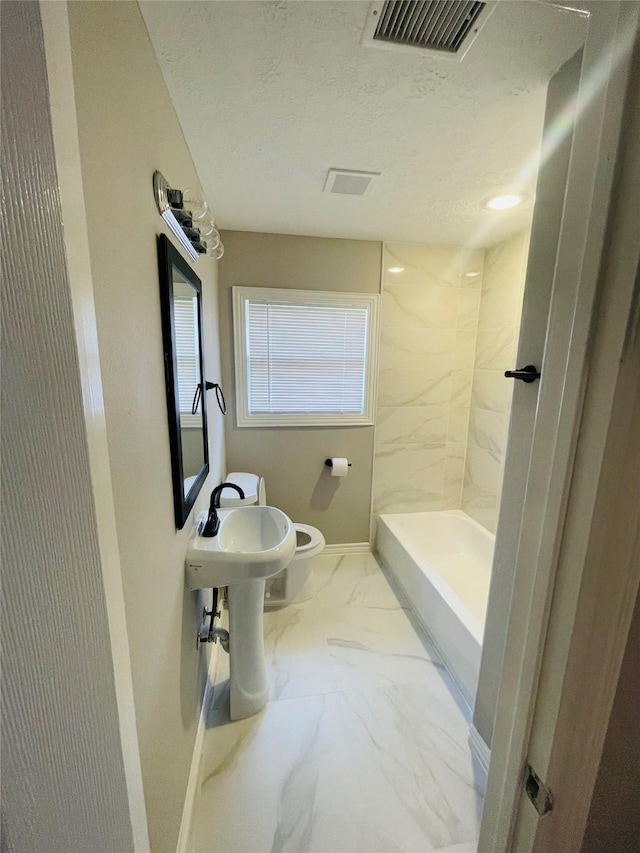 bathroom with a textured ceiling, toilet, visible vents, baseboards, and marble finish floor