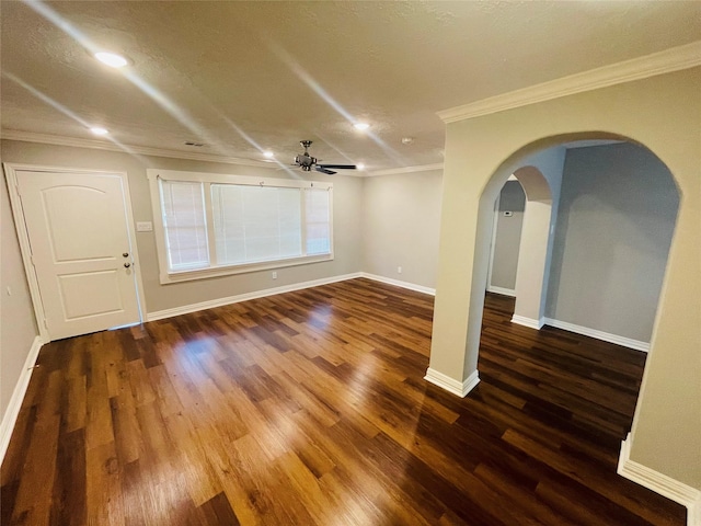 unfurnished room with arched walkways, crown molding, a ceiling fan, wood finished floors, and baseboards