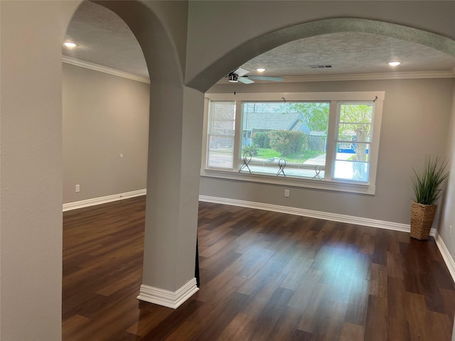 unfurnished room with arched walkways, crown molding, visible vents, and baseboards