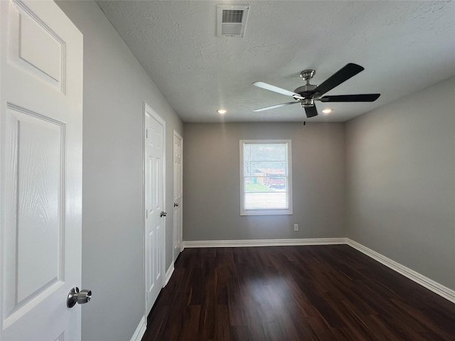 interior space featuring baseboards, visible vents, dark wood finished floors, and a textured ceiling