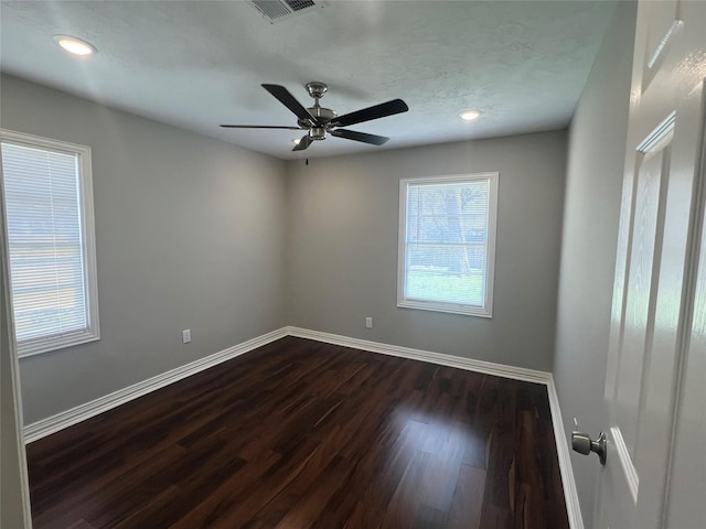 spare room featuring visible vents, baseboards, ceiling fan, dark wood-style flooring, and a textured ceiling