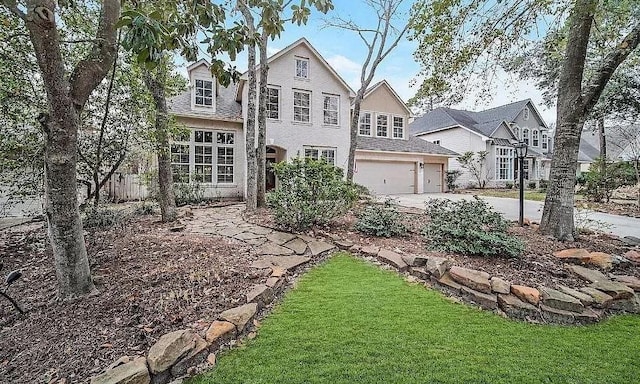 traditional-style home with a garage, concrete driveway, and a front lawn