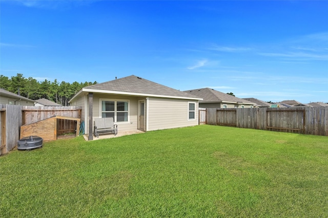 rear view of property with a fenced backyard, a lawn, and roof with shingles