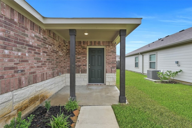 property entrance with brick siding, a lawn, and central AC unit