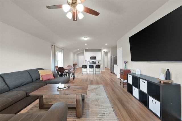 living area featuring light wood finished floors, a ceiling fan, and recessed lighting