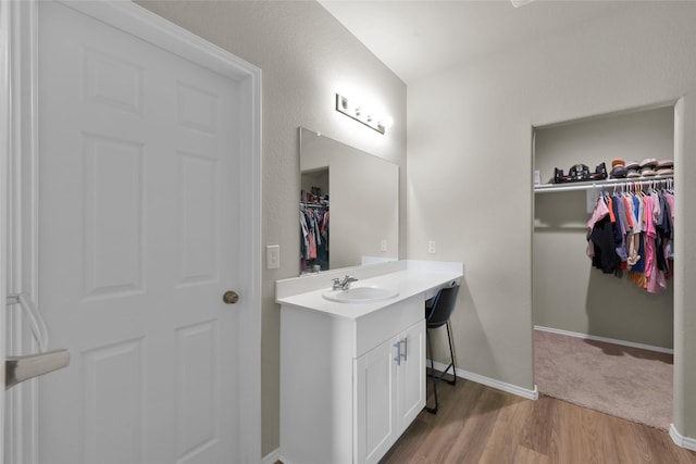 bathroom featuring a spacious closet, baseboards, wood finished floors, and vanity