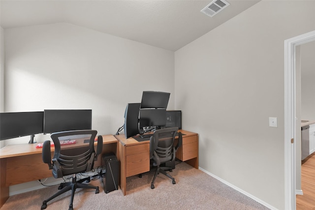 carpeted home office with lofted ceiling, baseboards, and visible vents