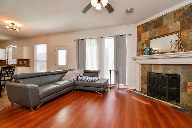 living room with crown molding, a fireplace, visible vents, and a healthy amount of sunlight