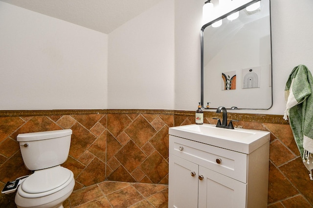 bathroom with a wainscoted wall, toilet, and tile walls