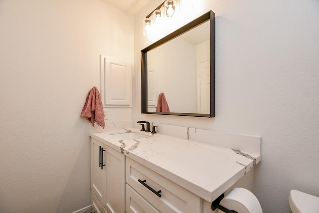 half bathroom featuring vanity, toilet, and baseboards