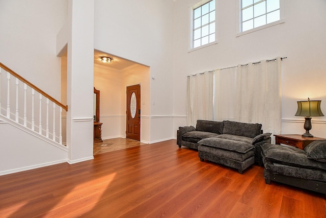 living area featuring baseboards, stairs, a towering ceiling, and wood finished floors