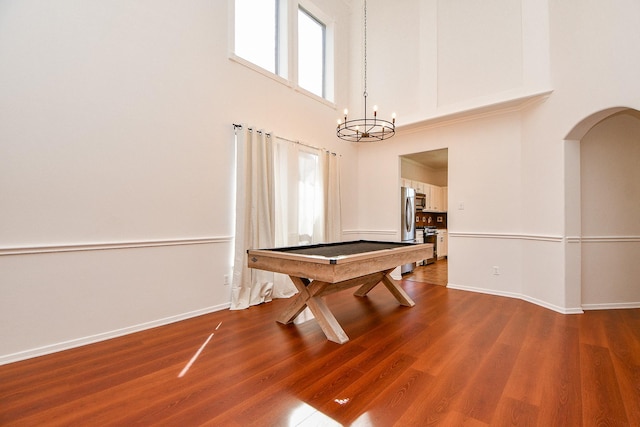 recreation room featuring arched walkways, a notable chandelier, billiards, and wood finished floors