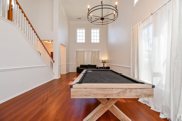 recreation room with ornamental molding, billiards, wood finished floors, a towering ceiling, and a chandelier