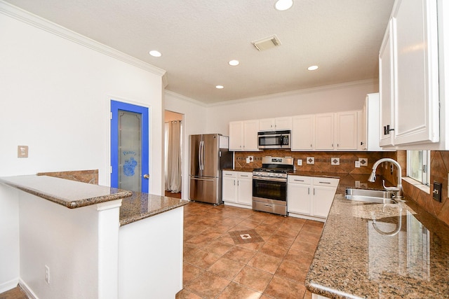 kitchen featuring visible vents, decorative backsplash, white cabinets, stainless steel appliances, and a sink