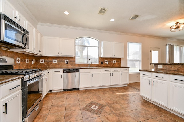 kitchen with dark countertops, visible vents, appliances with stainless steel finishes, and a sink