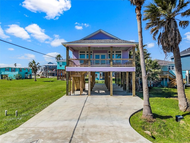 coastal inspired home featuring a carport, covered porch, driveway, and a front lawn