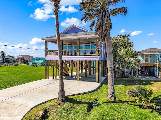 exterior space featuring a porch, a shingled roof, driveway, a carport, and a front yard