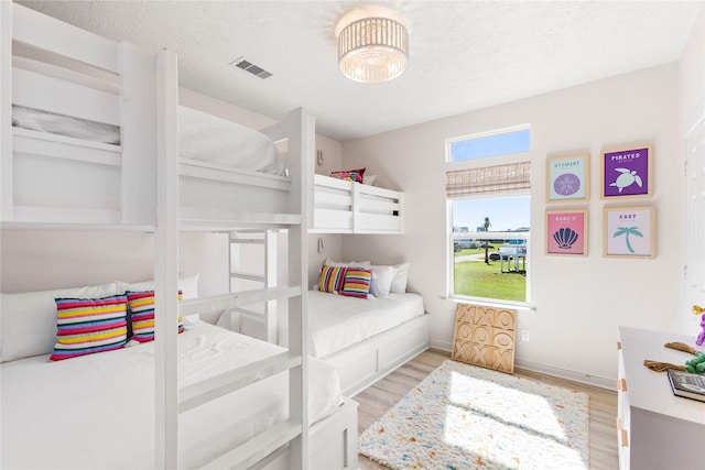 bedroom featuring a textured ceiling, baseboards, visible vents, and light wood-style floors