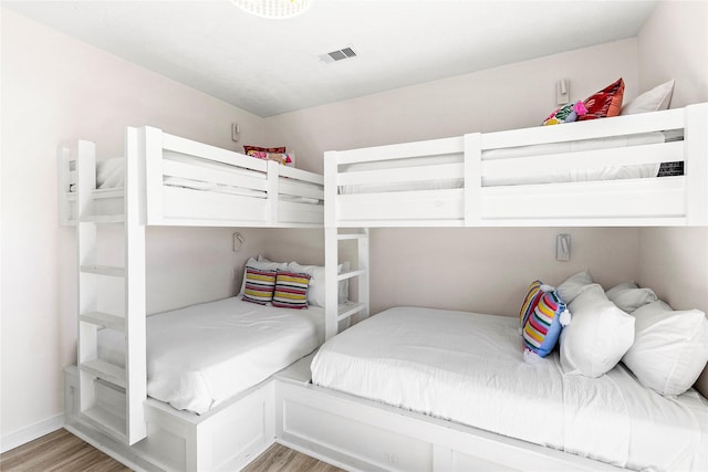 bedroom with light wood-style flooring, visible vents, and baseboards