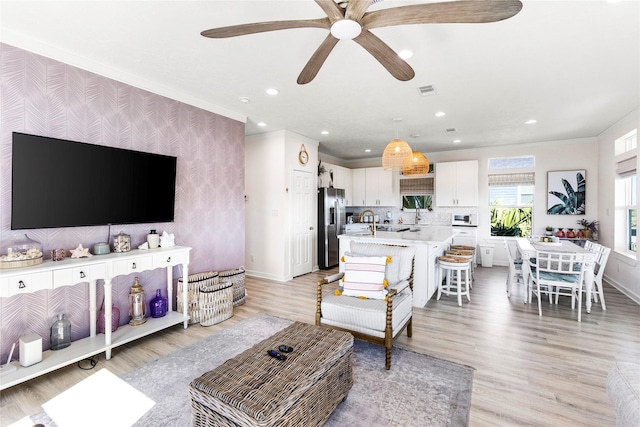 living room with recessed lighting, light wood-style flooring, an accent wall, baseboards, and wallpapered walls